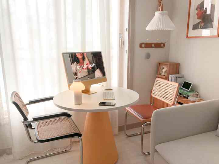 A simple living room in white and natural tones featuring a round table, sofa, and chairs