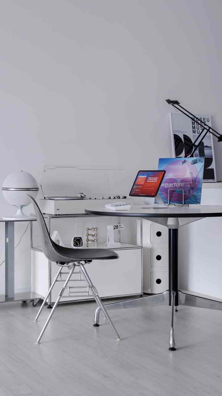 Monotone living room featuring a white round table, black chair, vintage turntable, and shelves with a minimalistic atmosphere
