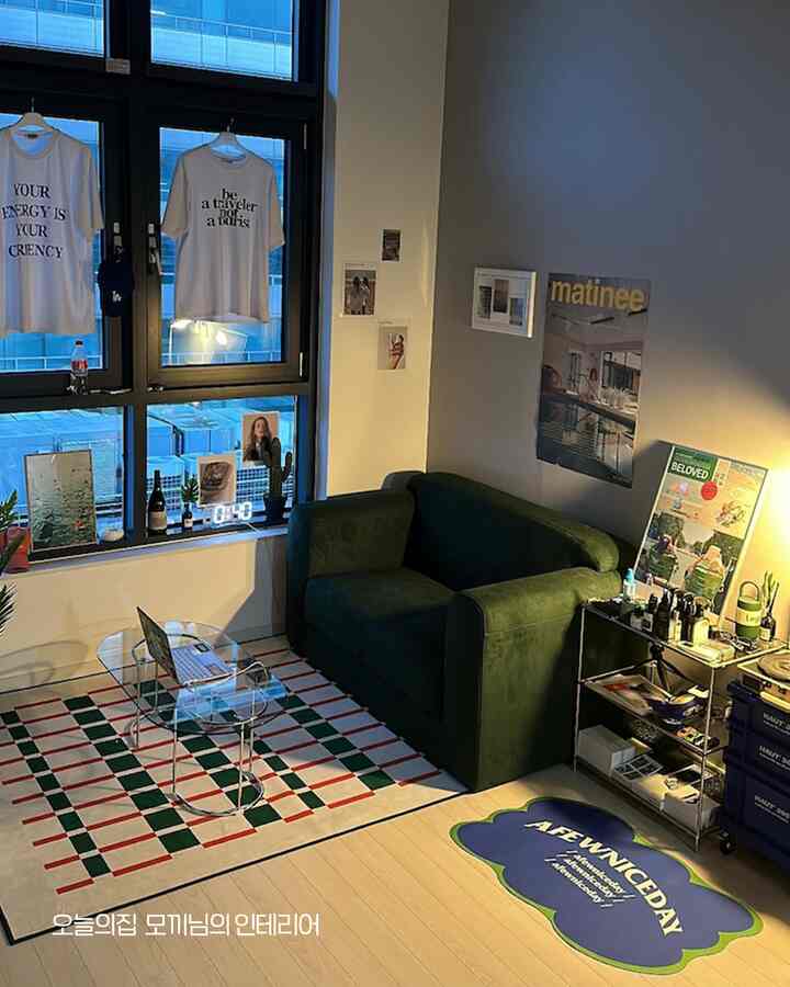 A cozy natural wood-toned living room featuring a green sofa and interior decor on the window sill, creating a modern ambiance