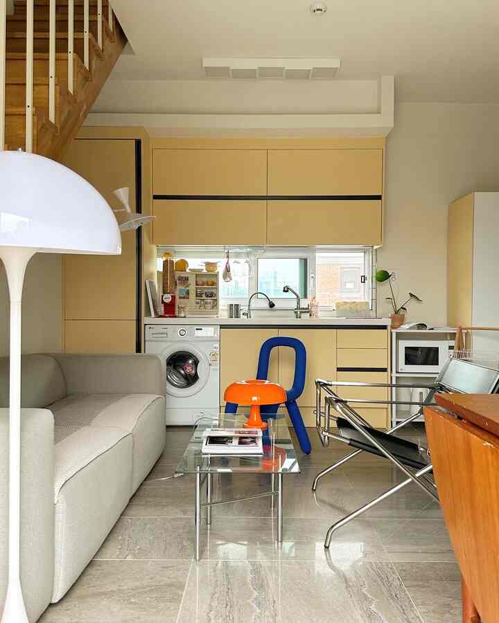 白とベージュのトーンのキッチン、ミッドセンチュリーモダンの家具と照明が配置された雰囲気のあるインテリア