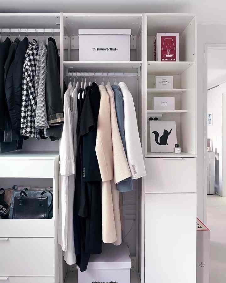 Clean white-toned walk-in closet storage featuring hanging clothes on rods, drawers, and shelves creating an organized space