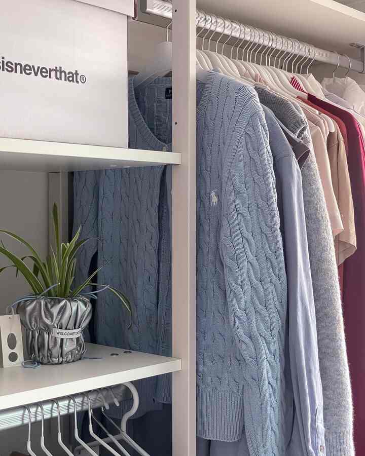 白を基調としたウォークインクローゼット、きちんと整理された洋服と収納棚のある落ち着いた空間