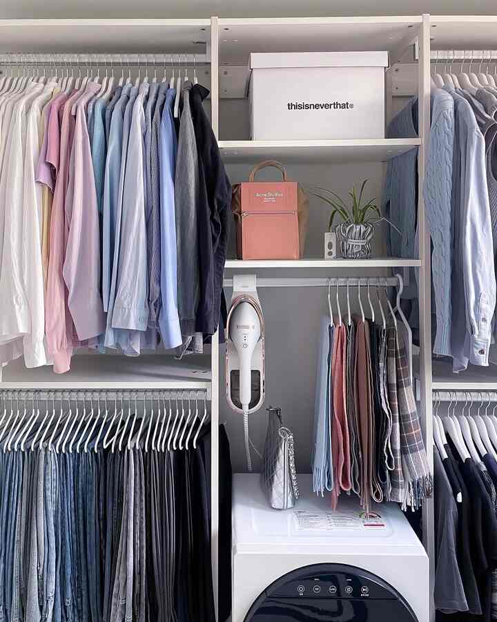 White and pastel toned walk-in closet featuring organized wardrobe, dryer, and steam iron creating a neat space