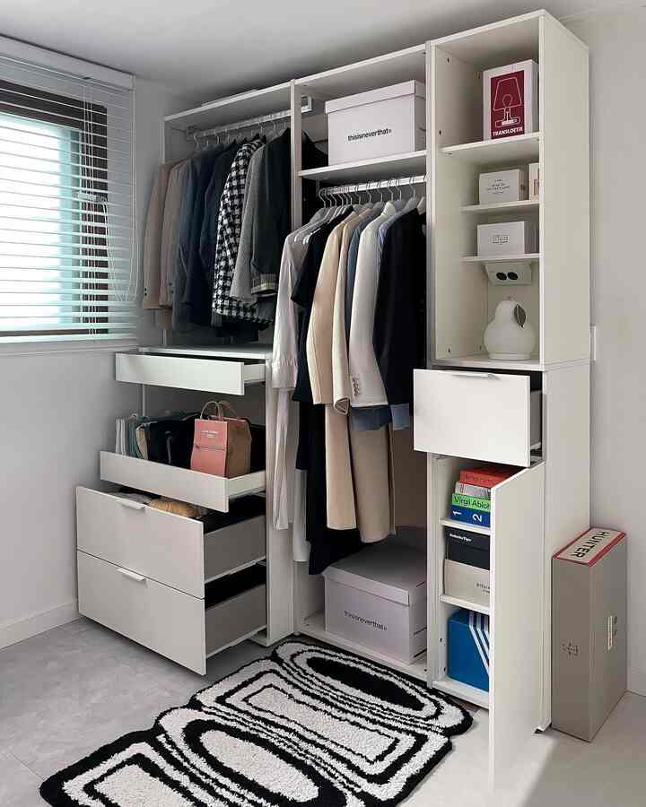 White-toned walk-in closet featuring neat hanging clothes and storage cabinets in a minimalistic space