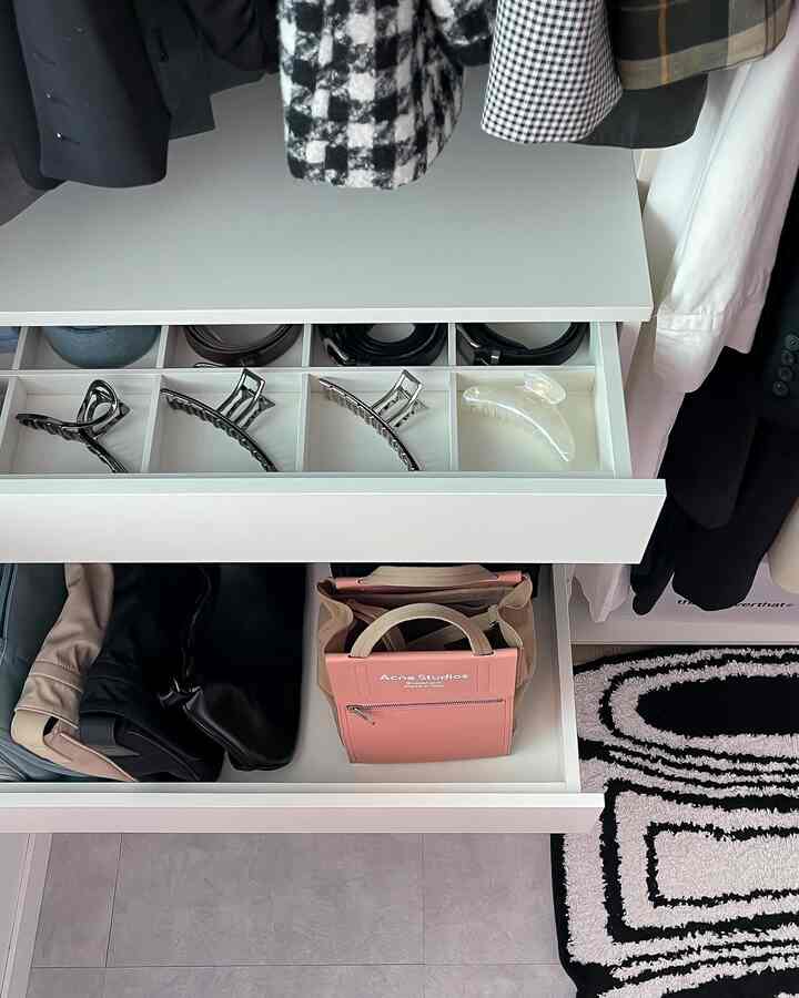 White-toned walk-in closet with organized drawers containing bags and accessories in a tidy space