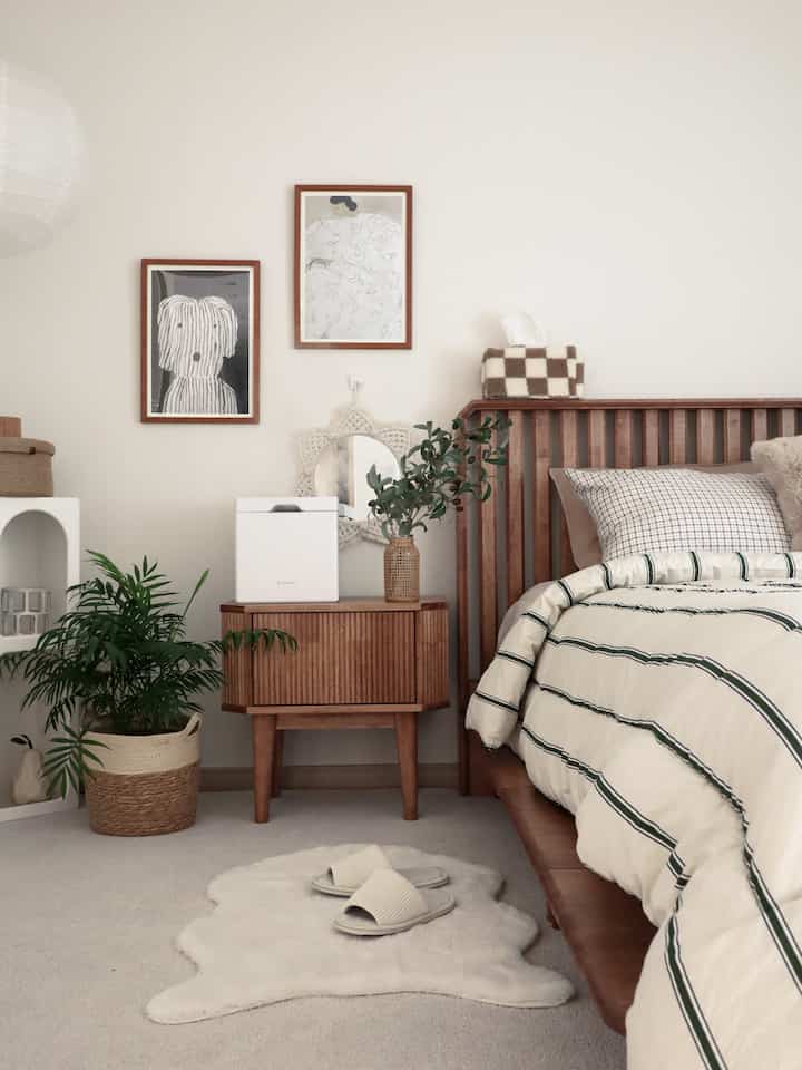 Ivory and wood-toned natural bedroom featuring wooden bed frame, nightstand, and a potted plant creating a cozy atmosphere