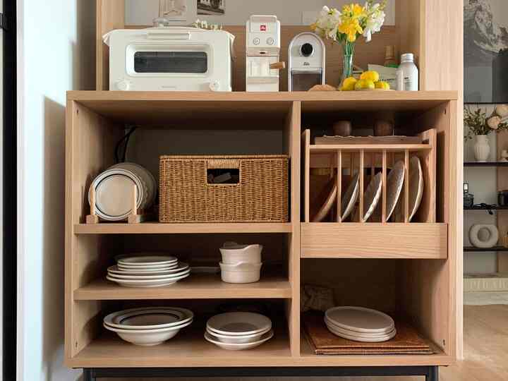 暖かみのある木目調のキッチンカフェキャビネット、上部にトースターとコーヒーマシン、下部にきれいに整理された皿やボウルが配置された雰囲気のあるインテリア