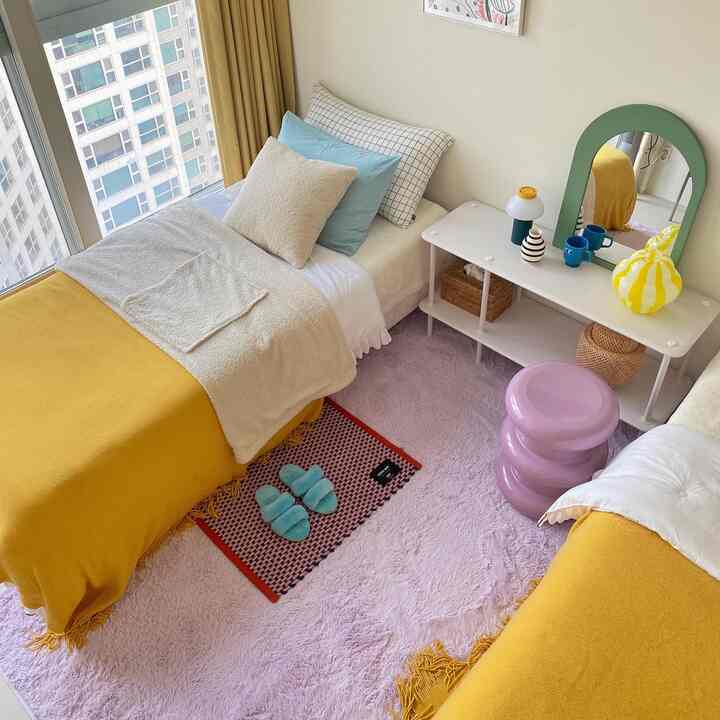 暖かいイエローとホワイトの色調の6畳寝室、柔らかいラグと整った寝具が配置された雰囲気のある空間