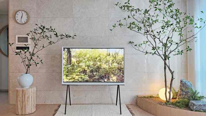 ナチュラルな木目調とベージュのタイル壁が調和したリビング、中央にサムスン セリフ TVと植物が配置されたミニマルな空間