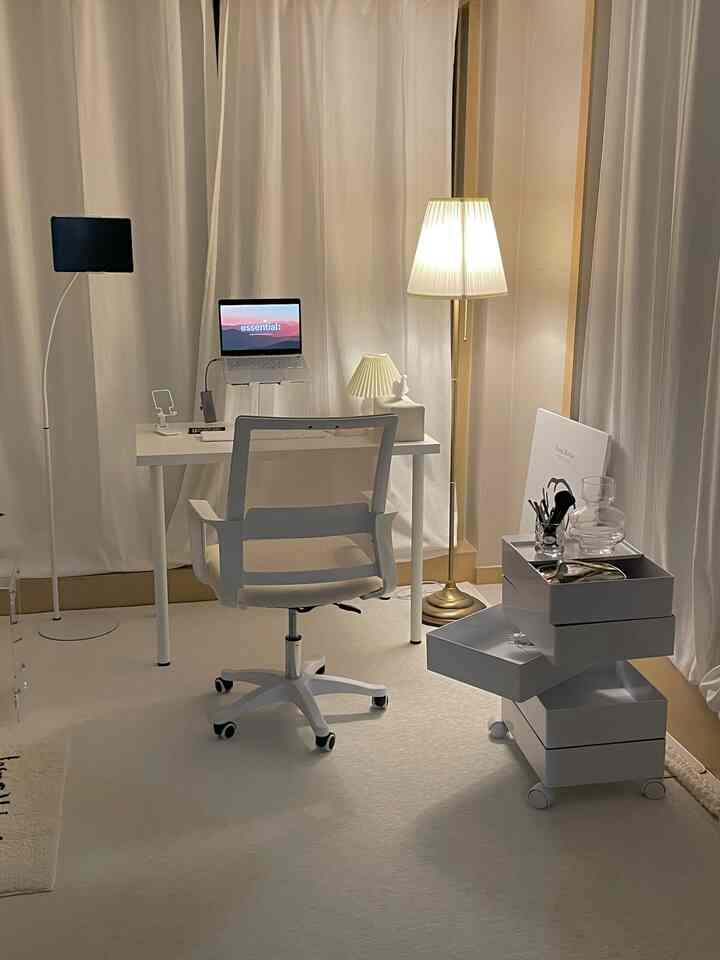 白とゴールドのトーンが調和したホームオフィス空間。机とオフィスチェア、収納ユニットが配置された、雰囲気のあるモダンな作業スペース