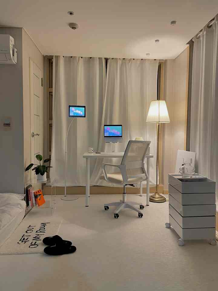白とゴールドのトーンのホームオフィス、デスクとオフィスチェア、フロアランプが配置されたシンプルモダンなインテリア
