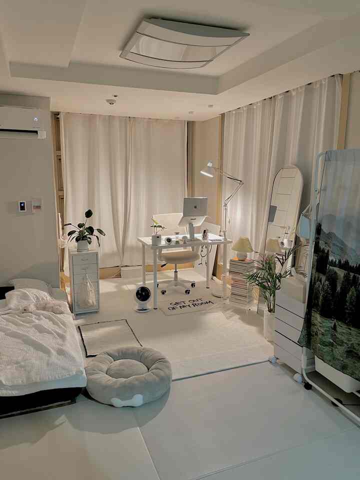 ホワイトとベージュの色調のバルコニー付き一人暮らしのホームオフィス空間、ベッドとデスク、ペットの犬が配置された温かみのあるインテリア