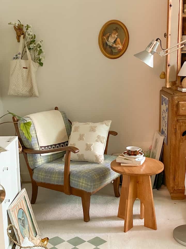 Beige and natural wood tone study featuring a checked fabric vintage sofa, wooden stool, and Artemide floor lamp creating a cozy reading nook