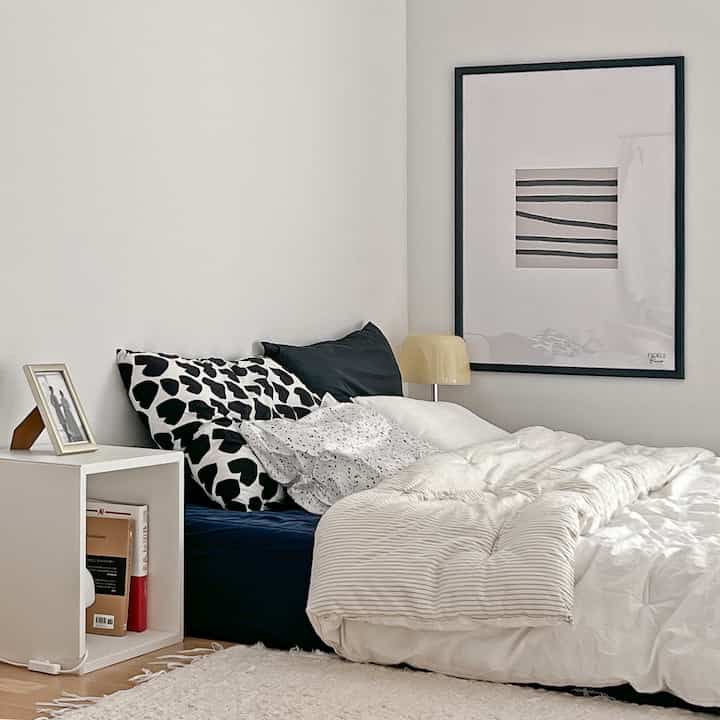 Simple bedroom featuring white and black tones, with bed and bedding creating a sleek atmosphere
