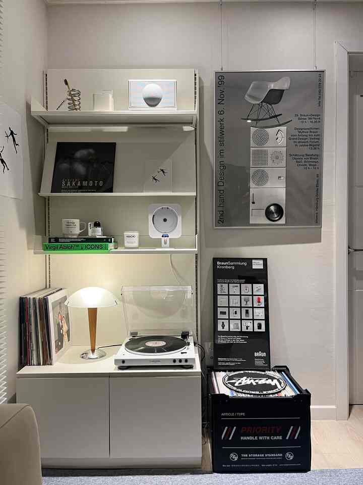 White and natural tone living room music zone featuring LP turntable, wall shelves, cabinet, and cozy lighting