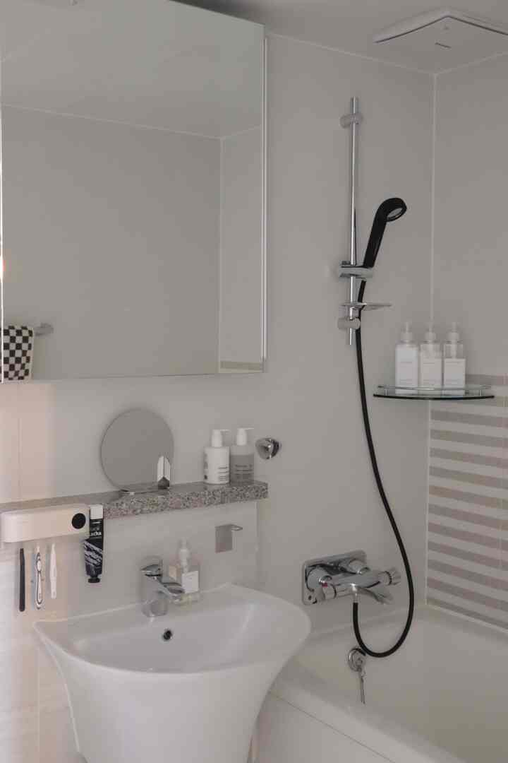 White toned bathroom featuring sink and bathtub with simple, hotel-like atmosphere