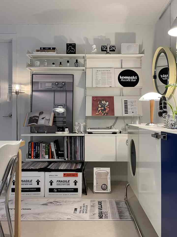 White and navy toned music space featuring a turntable, LP storage, vintage wall art, and modern lighting