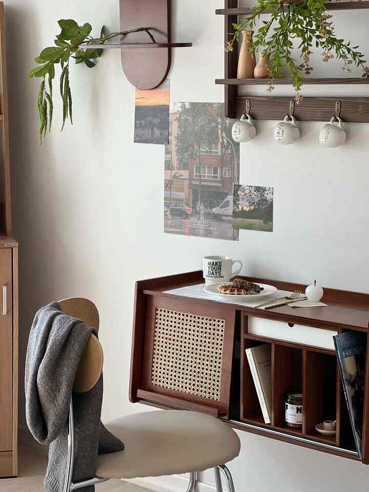 ナチュラルな木目調とラタン素材のキャビネットが壁に設置され、上にコーヒーとクロッフルが置かれた雰囲気のあるおうちカフェのインテリア