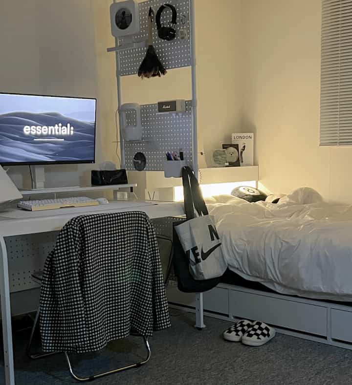 White and black accented 8-pyeong studio apartment with modern mid-century style featuring bed, desk, and pegboard partition in a neat single household space