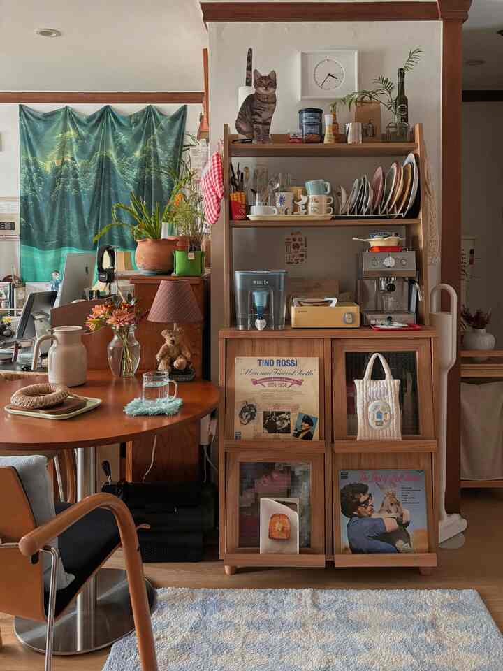 白い壁と木目調の家具が調和したキッチン、猫の装飾と多彩なキッチン用品が配置された雰囲気のあるインテリア