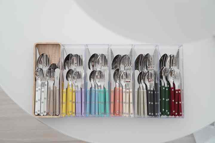 Colorful cutlery neatly organized in transparent storage box on a clean kitchen surface
