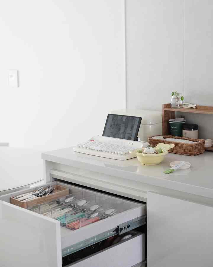 白を基調としたキッチン、透明な引き出しにカトラリーが整頓された清潔感のあるモダンなインテリア