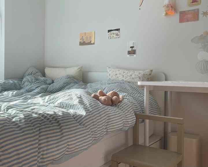 明るくナチュラルな色調の寝室、青いストライプの掛け布団とキッズチェアが配置された雰囲気のあるインテリア