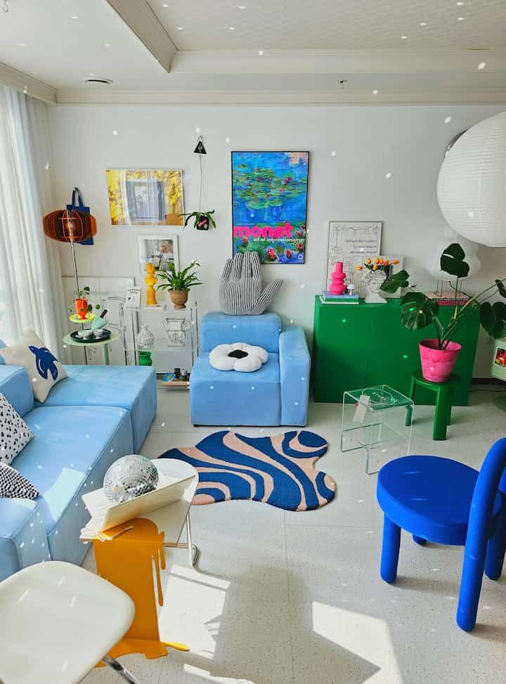Bright-toned living room featuring blue modular sofa, mirror ball, and various plants creating a lively atmosphere