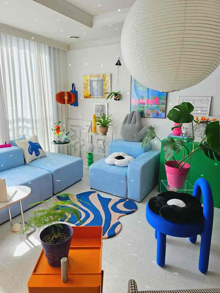 Bright and cozy mid-century modern living room with white walls and blue modular sofas, decorated with colorful accessories and plants