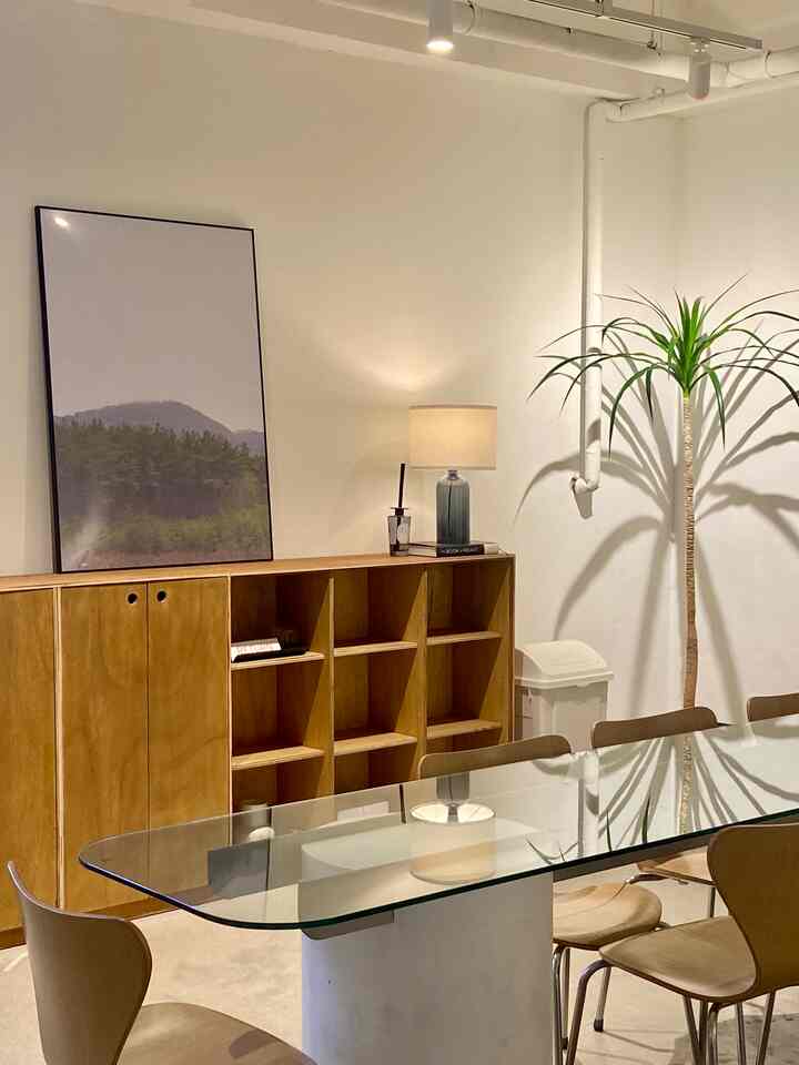 ナチュラルな木目調とホワイトトーンのカフェ風ホームカフェ空間、ガラスのダイニングテーブルと木製の椅子、テーブルランプやプランテリアが調和した温かみのあるインテリア