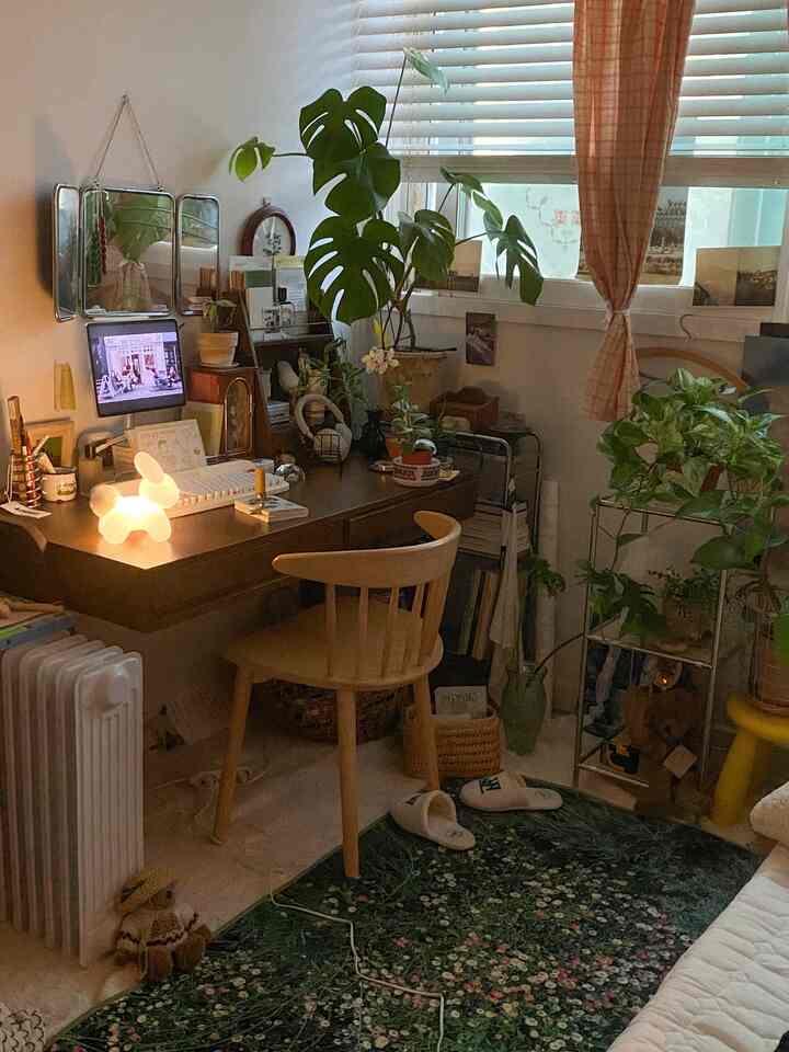 温かみのあるウッドトーンと緑の植物が配置されたヴィンテージ感あふれるワンルームの書斎スペース