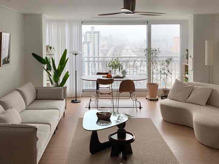 明るいホワイトと木目調のリビング、ファブリックソファと丸いダイニングテーブルが配置された自然な雰囲気のあるインテリア