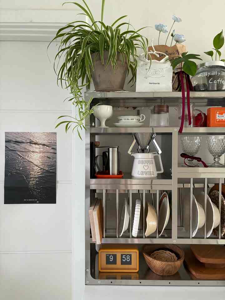 シルバーの金属製キッチンラックと食器、植物、ポスターが配されたナチュラルモダンなホームカフェ空間