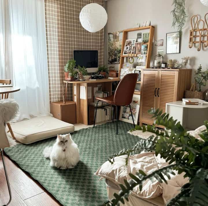 Vintage green rug in living room with wooden desk and chair, a cat sitting centrally, creating a warm atmosphere