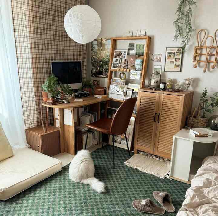 Natural wood tones and green rug define this bedroom and home office space, featuring a cat and warm cozy decor.