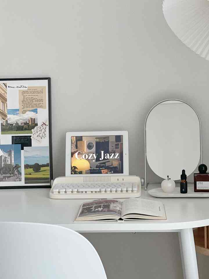 白を基調としたホームオフィス、半円形の白いデスクにレトロなキーボード、鏡、ディフューザーが置かれたシンプルモダンなインテリア