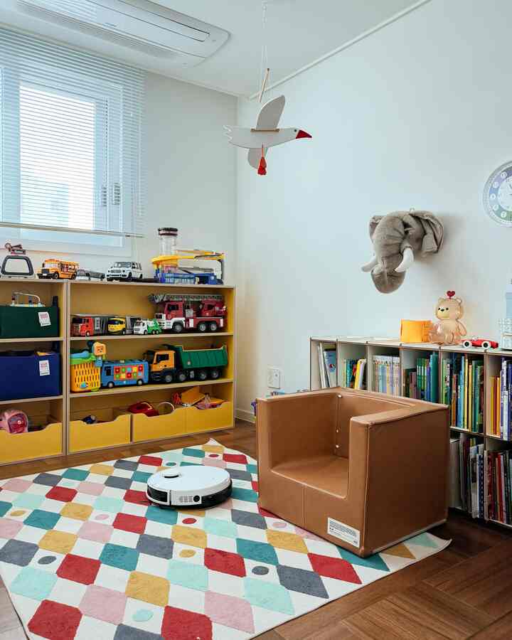 ホワイトと木目調の子供部屋、玩具収納棚とカラフルなラグが配置された雰囲気のある空間