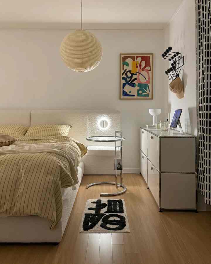 A cozy hotel-like bedroom in warm natural and white tones featuring striped bedding and modern furniture