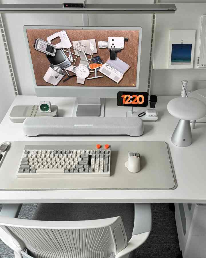 白とグレーのトーンが調和したホームオフィス、モニターやキーボード、スピーカーが配置されたミニマルなデスクインテリア