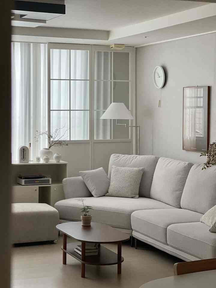 白と木目調のリビング、スタイリッシュなコーナーソファとコーヒーテーブルが配置された自然なモダンな雰囲気のインテリア