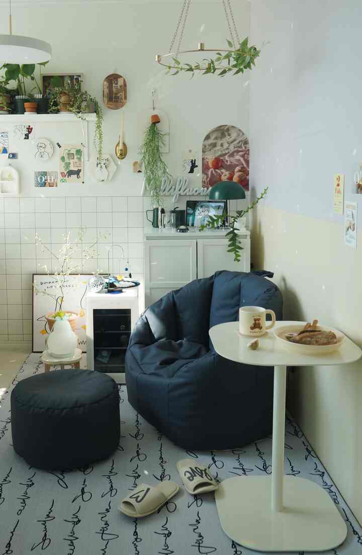 ホワイトとネイビーの色調のリビングアルファルーム、ビーズクッションソファとスツール、サイドテーブルが配置された雰囲気のある空間