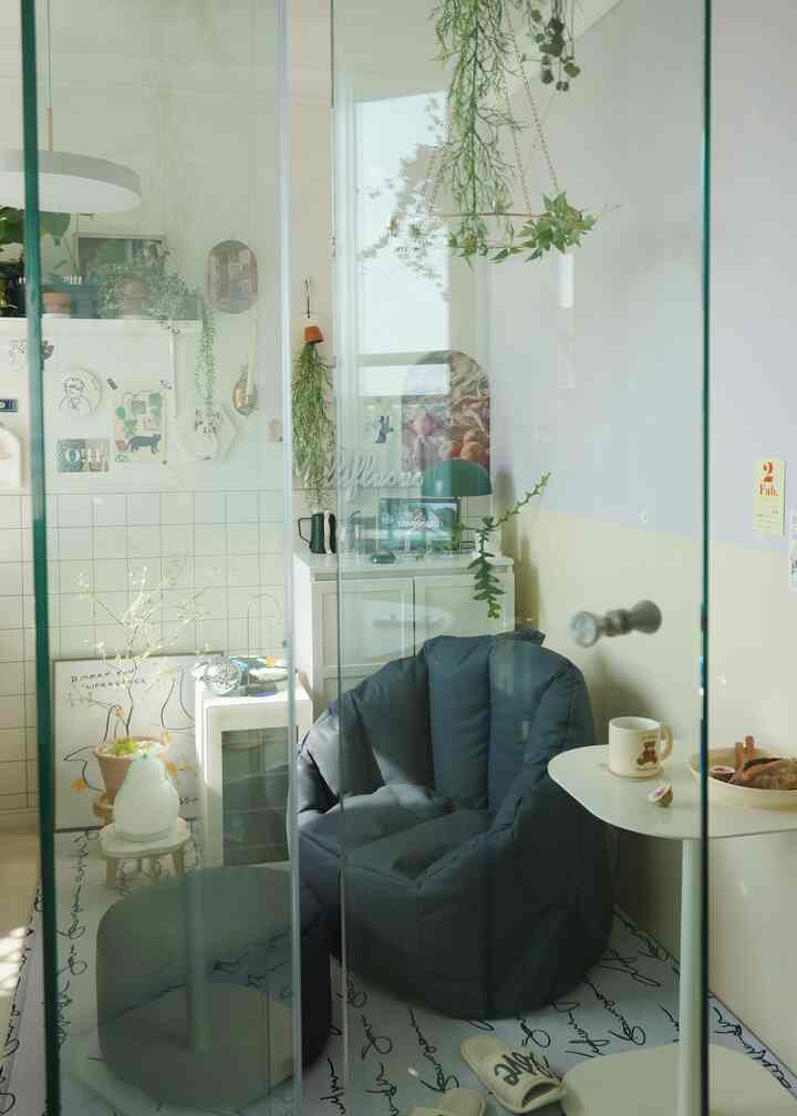 ホワイトとブラックを基調とした小さなホームライブラリー、ビーズクッションソファ、植物、コーヒーテーブルが配置された落ち着いた雰囲気のインテリア