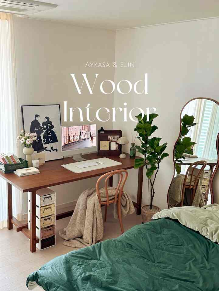 ナチュラルな木目調家具と緑の寝具、大きな植物と鏡が配置された寝室兼ホームオフィスの雰囲気あるインテリア