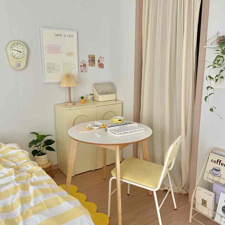 柔らかな黄色と木目調が調和する寝室の一角にある温かみのあるおうちカフェ、丸テーブルとかわいらしい小物が配置された印象的な空間