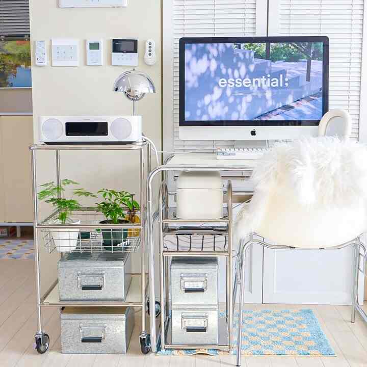 白と銀色のトーンが特徴のモダンなホームオフィス、金属製の収納カートと無印良品のトタンボックスが整然と配置された空間