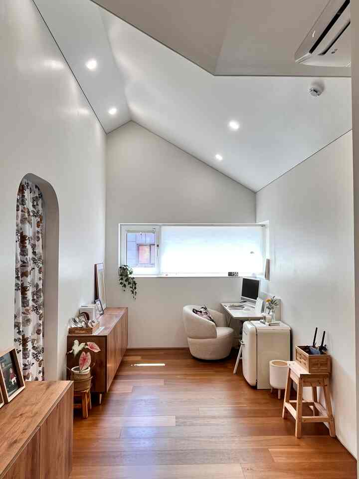 白とウッドトーンが調和したシンプルモダンな書斎、コンピューターデスクとクリーム色の椅子が配置された雰囲気ある作業空間