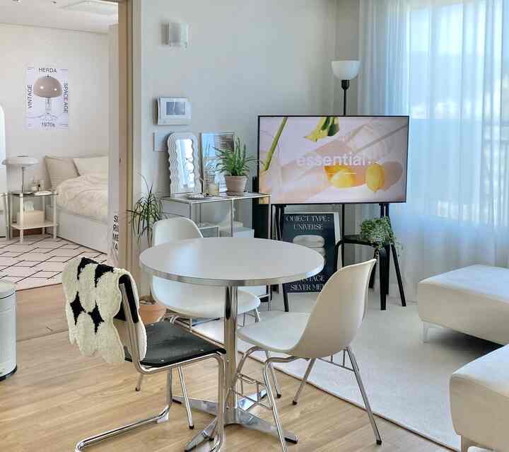 明るいホワイトとナチュラルカラーのリビング、丸テーブルと白いソファが配置された清潔感のあるモダンな空間