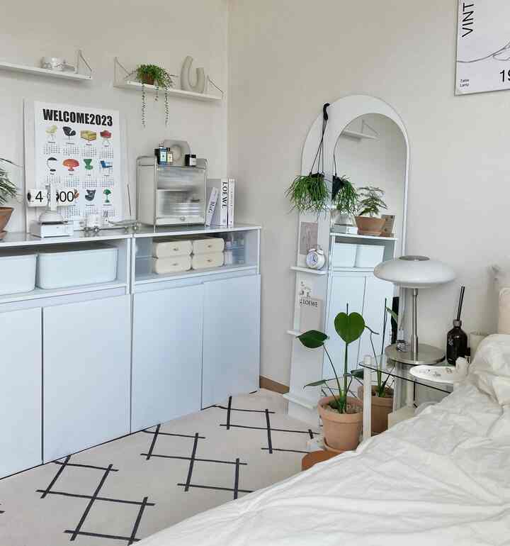 ホワイトとベージュの調和がとれた寝室、広いキャビネットと全身鏡が配置され、自然な雰囲気のあるインテリア