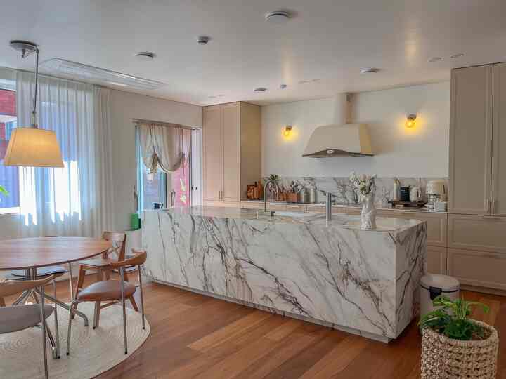 ベージュ調で大理石のキッチンアイランドが配置されたキッチン、温かみのあるモダンなインテリア