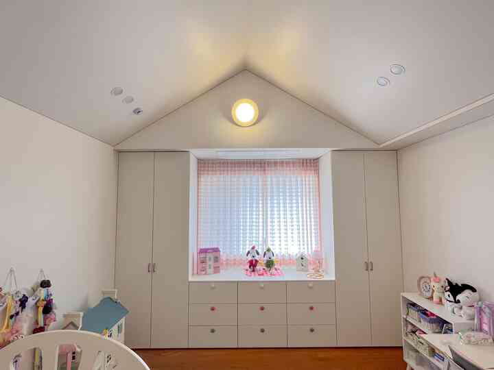白とピンクの色調の子供部屋、ドレッサーとワードローブが配置された落ち着いた娘の部屋のインテリア
